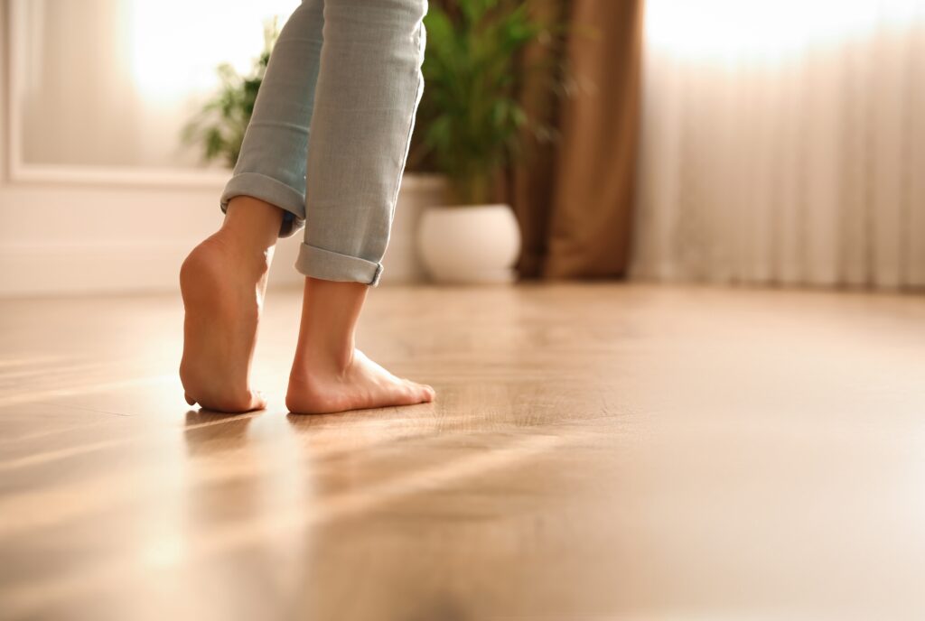 Barefoot woman at home, closeup. Floor heating system