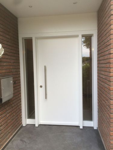 Weiße moderne Eingangstür mit Glaselementen, umgeben von Ziegelwänden.