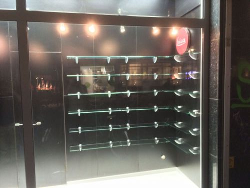 Leeres Regal in einem Schaufenster, beleuchtet, mit schwarzem Hintergrund und Leica-Logo.