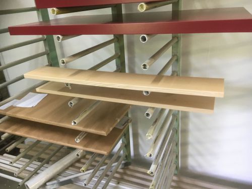 Regale mit Holzplatten in Rot und Naturfarbe, gestapelt auf weißen Rohren.